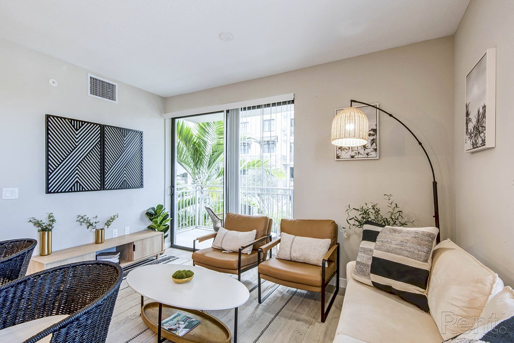 A living room with a white couch, a coffee table, and a large window at Mayla Pompano, Pompano Beach, FL