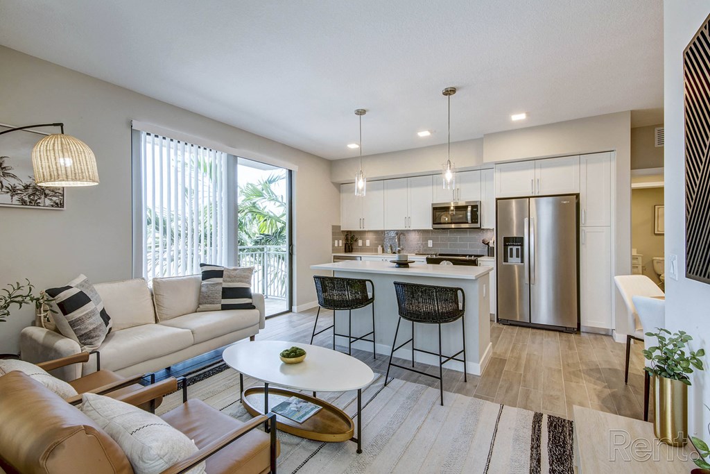 A modern kitchen with a breakfast bar and a dining table with chairs at Mayla Pompano, Pompano Beach