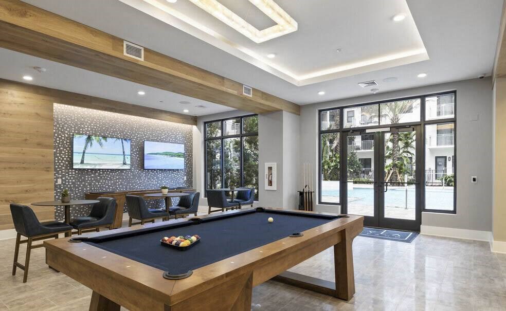 A pool table is in the middle of a room with a view of the outside at Mayla Pompano, Pompano Beach, FL