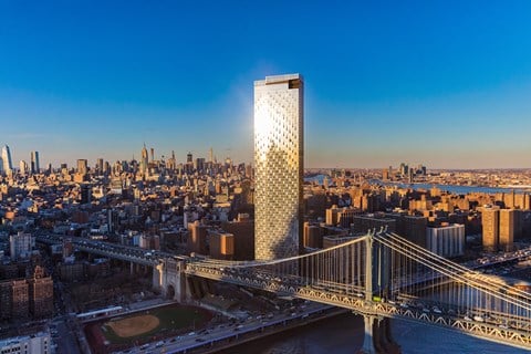 a tall skyscraper overlooking a city with the brooklyn bridge