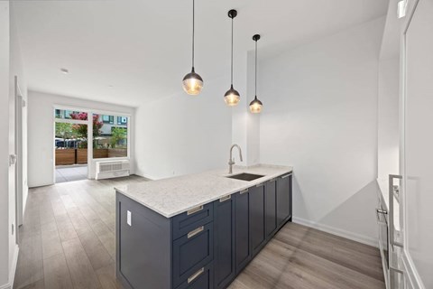 A kitchen with a sink and cabinets under a window.