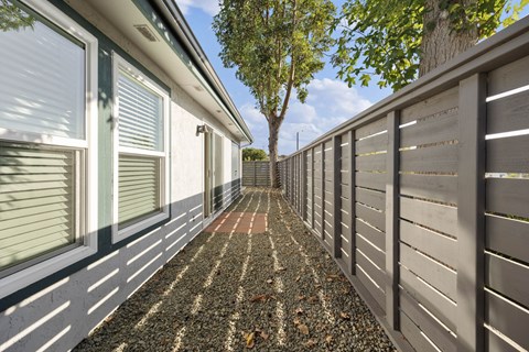 A long, narrow walkway between two walls with a tree in the distance.