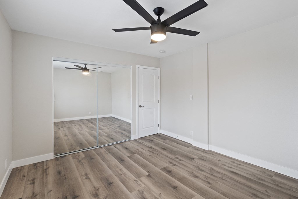 an empty bedroom with a ceiling fan and a mirrored closet at Charle Square Apartments, Costa Mesa, 92627