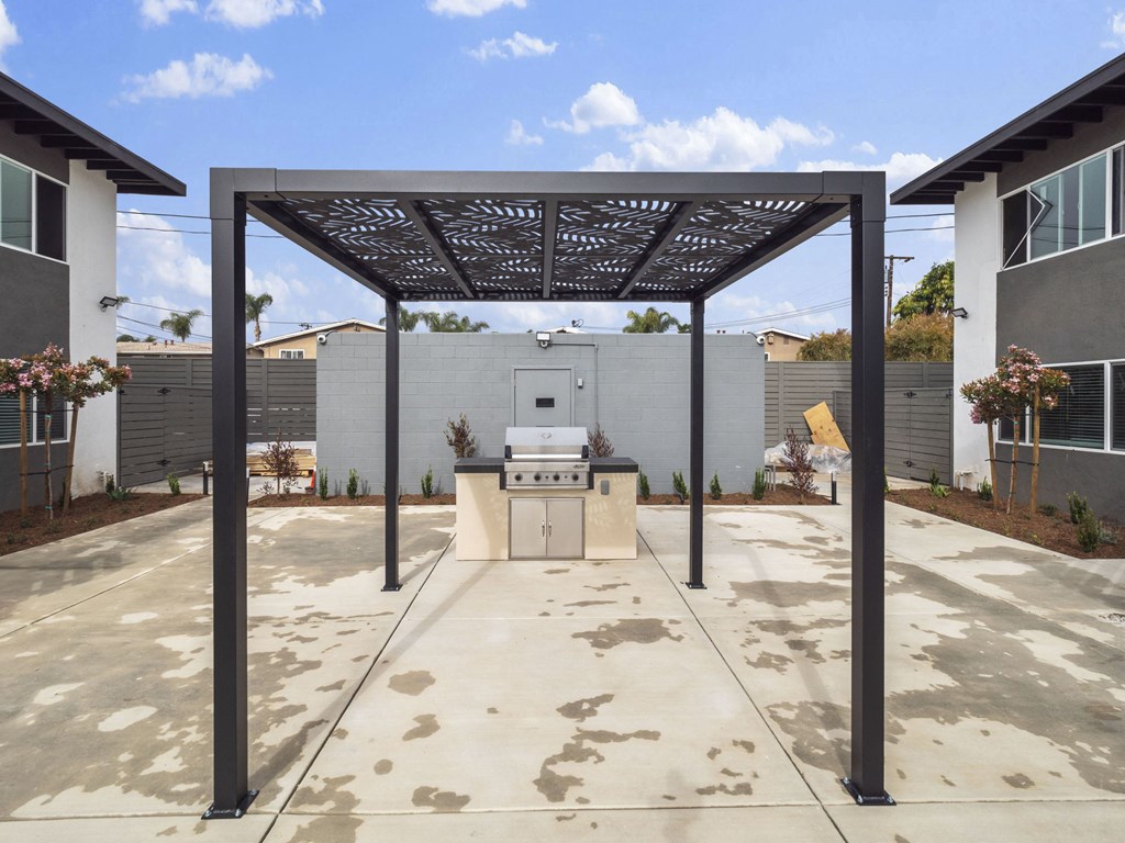 a patio with an outdoor kitchen and a pergola at Charle Square Apartments, Costa Mesa, California