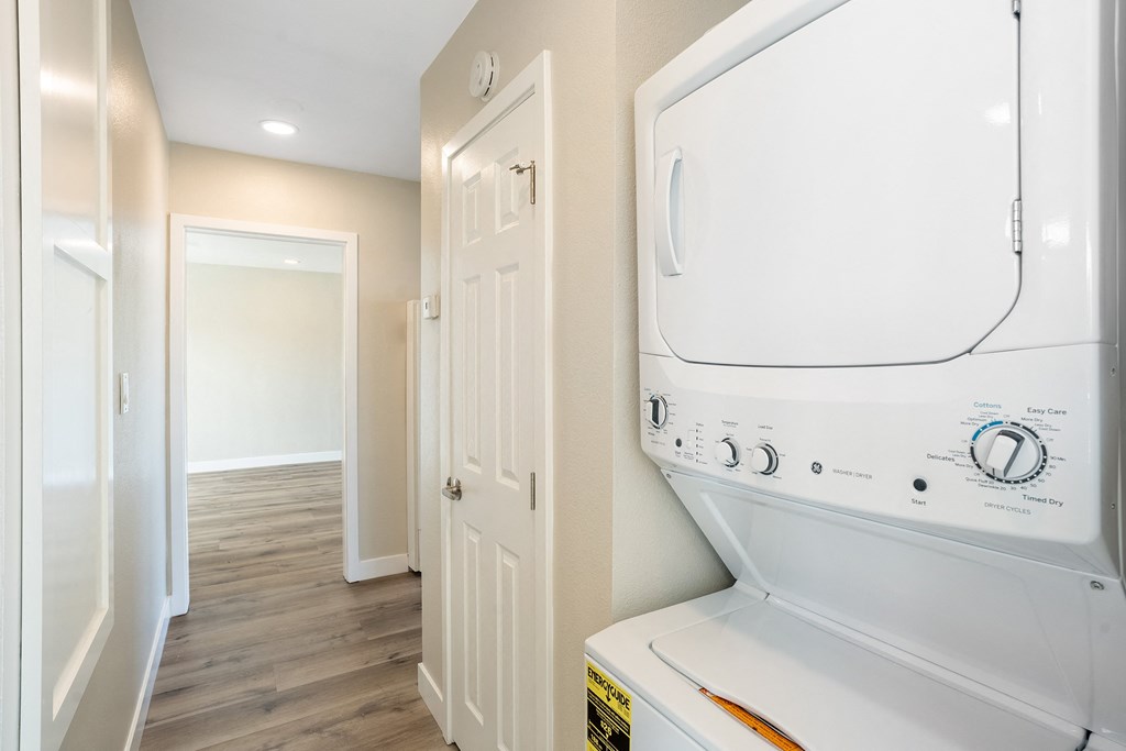 a laundry room with a washer and dryer and a hallway with a door at Huntington Manor Homes Apartment, California, 92648