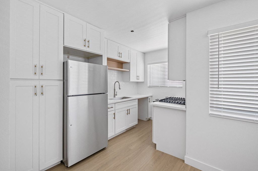 a white kitchen with white cabinets and a stainless steel refrigerator at Arlington Square Apartment, Torrance, CA, 90501