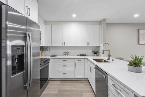 A modern kitchen with a stainless steel refrigerator and white cabinets.