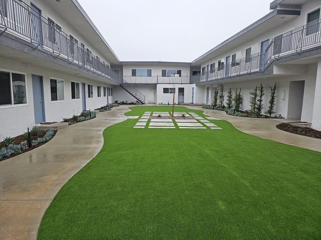 the courtyard of an apartment building with green grass