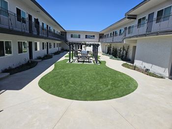 a courtyard with a table and chairs in the middle of an apartment building