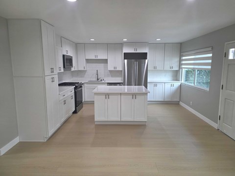 A kitchen with white cabinets and a wooden floor.