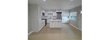 A kitchen with white cabinets and a wooden floor.