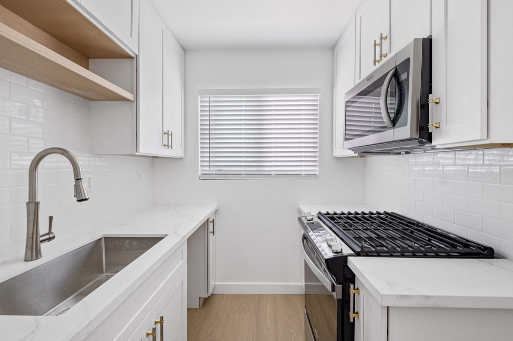 a kitchen with white cabinets and a stove and a microwave at Arlington Square Apartment , California, 90501