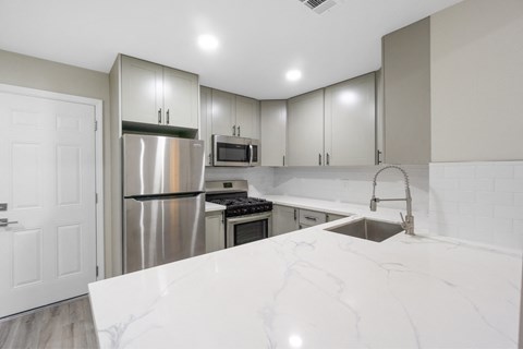 a kitchen with white marble counter tops and stainless steel appliances