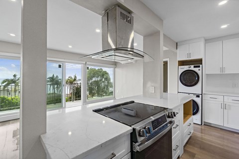 A modern kitchen with a stove top oven and a washing machine built into the cabinetry.