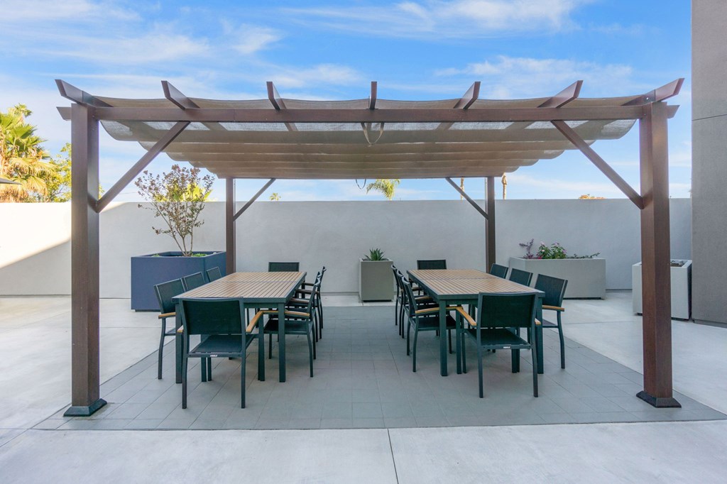 A patio with a table and chairs under a wooden pergola.at The Reserve La Mirada, California, 90638
