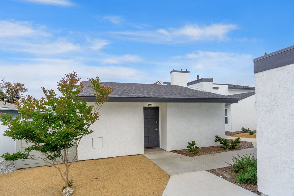 the front entrance to a white house with a black door
