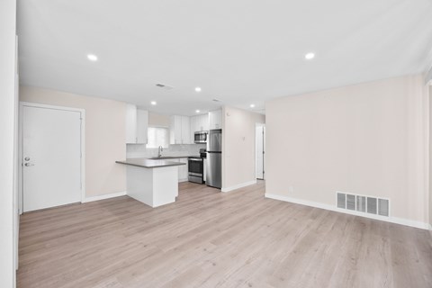 A kitchen with a white countertop and wooden flooring.
