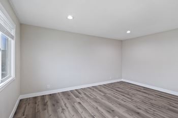 an empty room with wood-like floors, recessed lighting,  and white walls