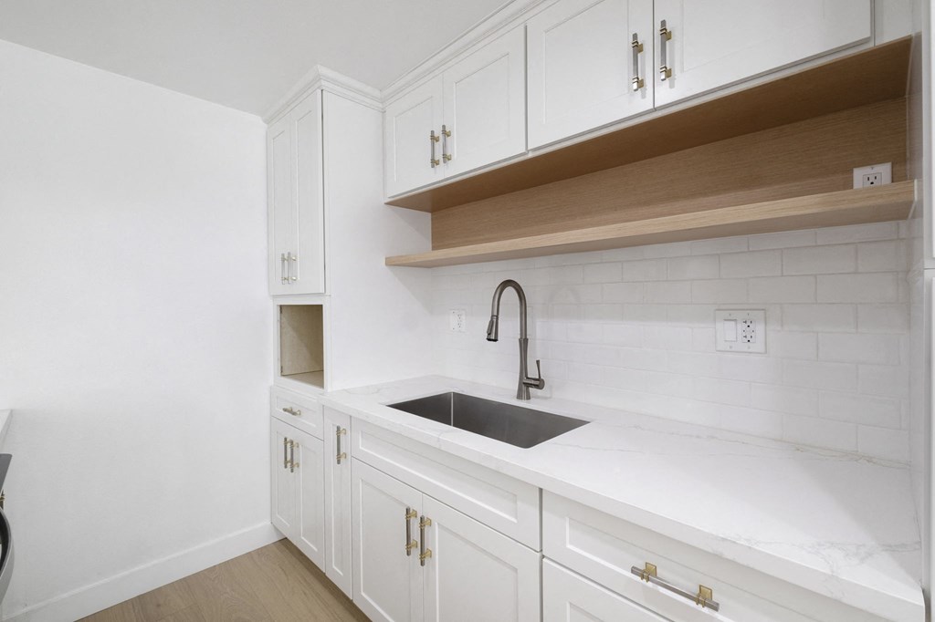 A kitchen with white cabinets and a black sink at Arlington Square Apartment , California
