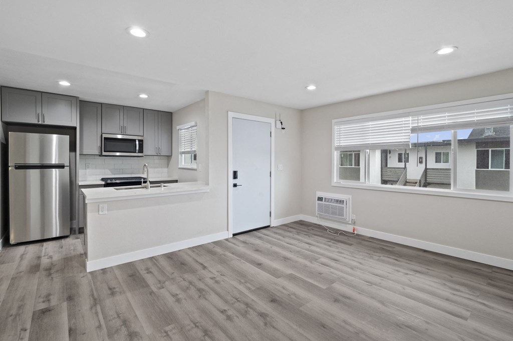 an empty kitchen and living room with a refrigerator and a sink at Charle Square Apartments, Costa Mesa, California