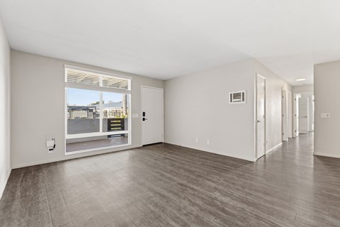 A spacious room with a large window and wooden flooring.