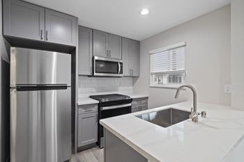 an empty kitchen with stainless steel appliances and white countertops