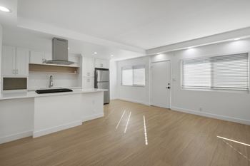 A kitchen with white cabinets and a wooden floor.