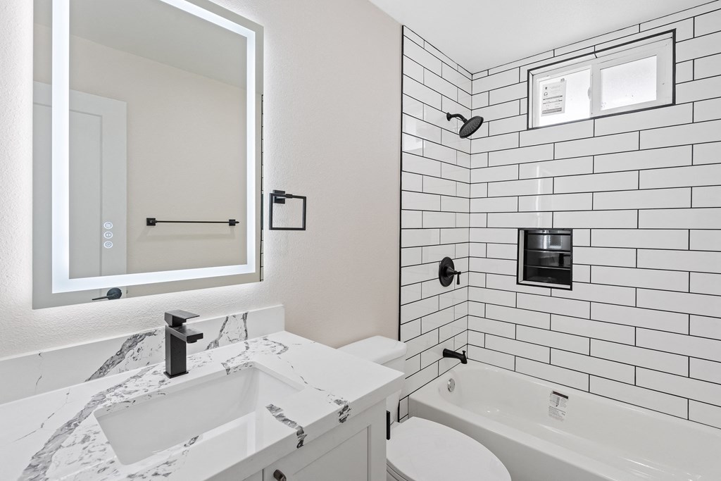 a bathroom with white tiles and a white tub and sink at Seaview Terrace Apartment Homes, California, 92672