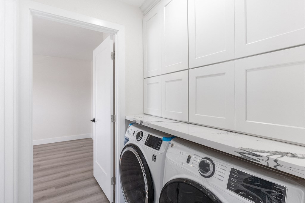 a laundry room with white cabinets and a white washer and dryer at Seaview Terrace Apartment Homes, California