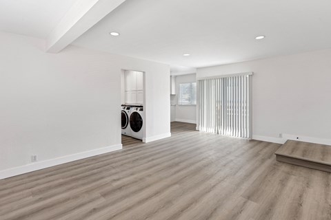 a renovated living room and laundry room with white walls and wood floors
