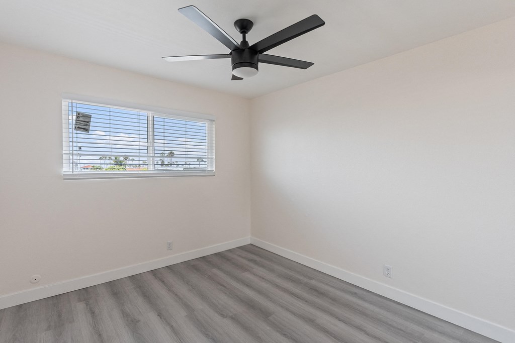 a bedroom with a ceiling fan and a window at Seaview Terrace Apartment Homes, San Clemente, California