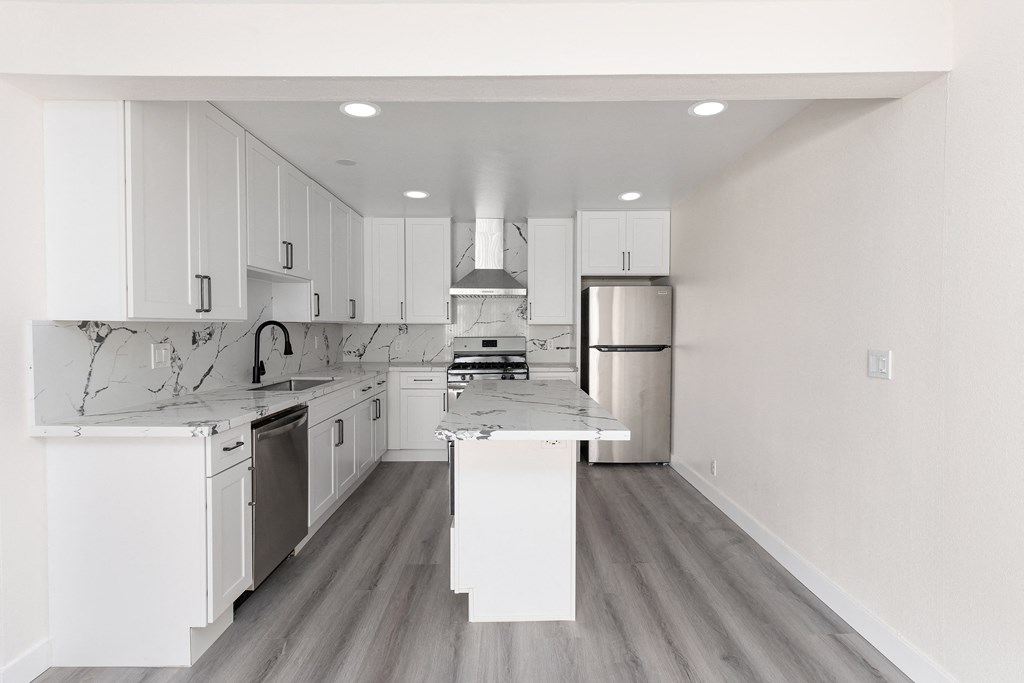 a black and white photo of a kitchen with white cabinets and stainless steel appliances at Seaview Terrace Apartment Homes, San Clemente