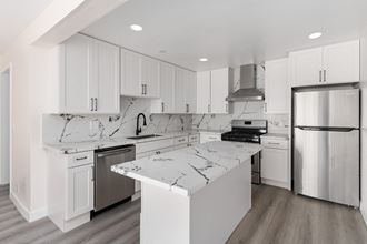 a kitchen with white cabinets and white marble countertops