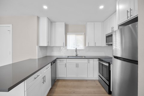 A modern kitchen with white cabinets and a stainless steel refrigerator.