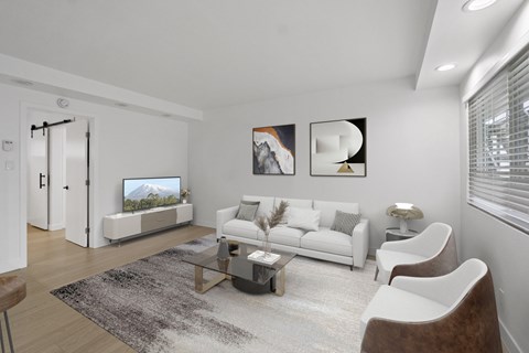 A modern living room with a white sofa, a glass coffee table, and a TV.