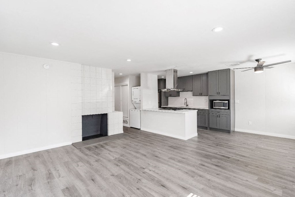 an empty living room and kitchen with a wood floor