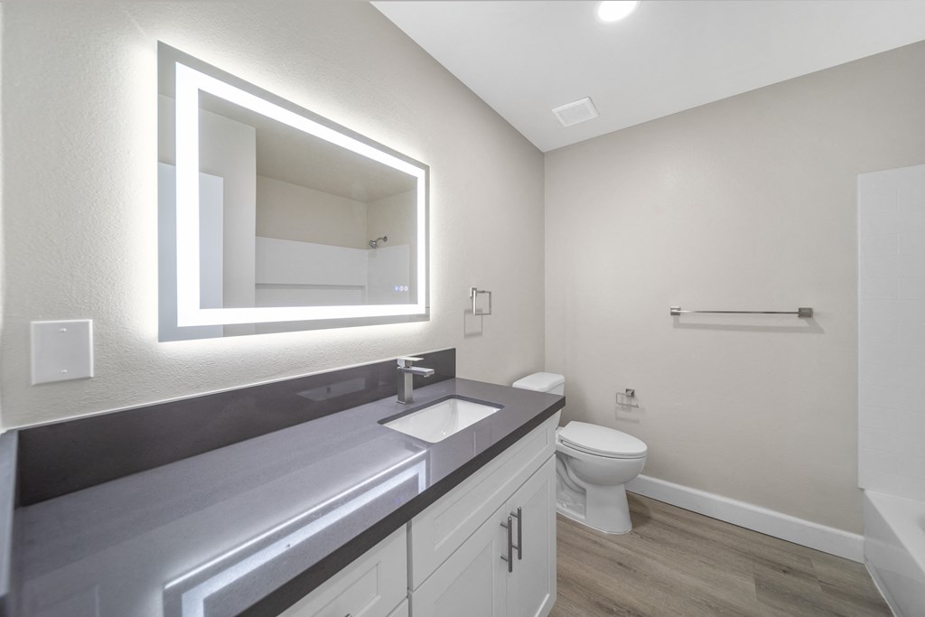 a bathroom with a large mirror and a sink and a toilet a bathroom with a large mirror and a sink and a toilet at Wescove Apartments, West Covina
