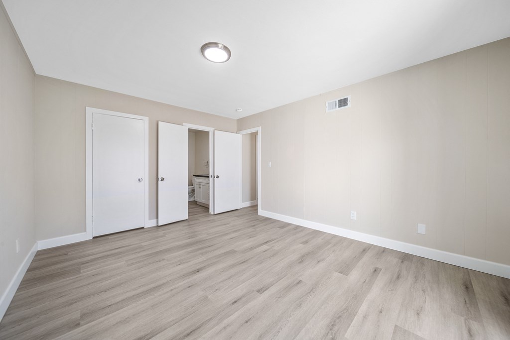 an empty living room with wood floors and white walls