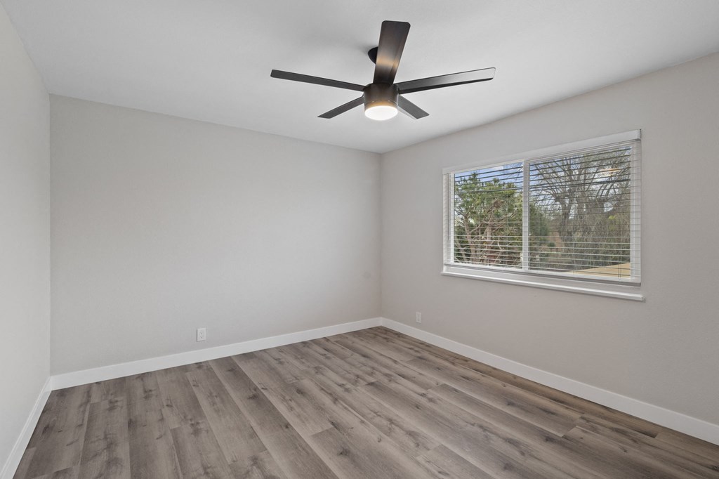an empty bedroom with a window and a ceiling fan at Charle Square Apartments, California