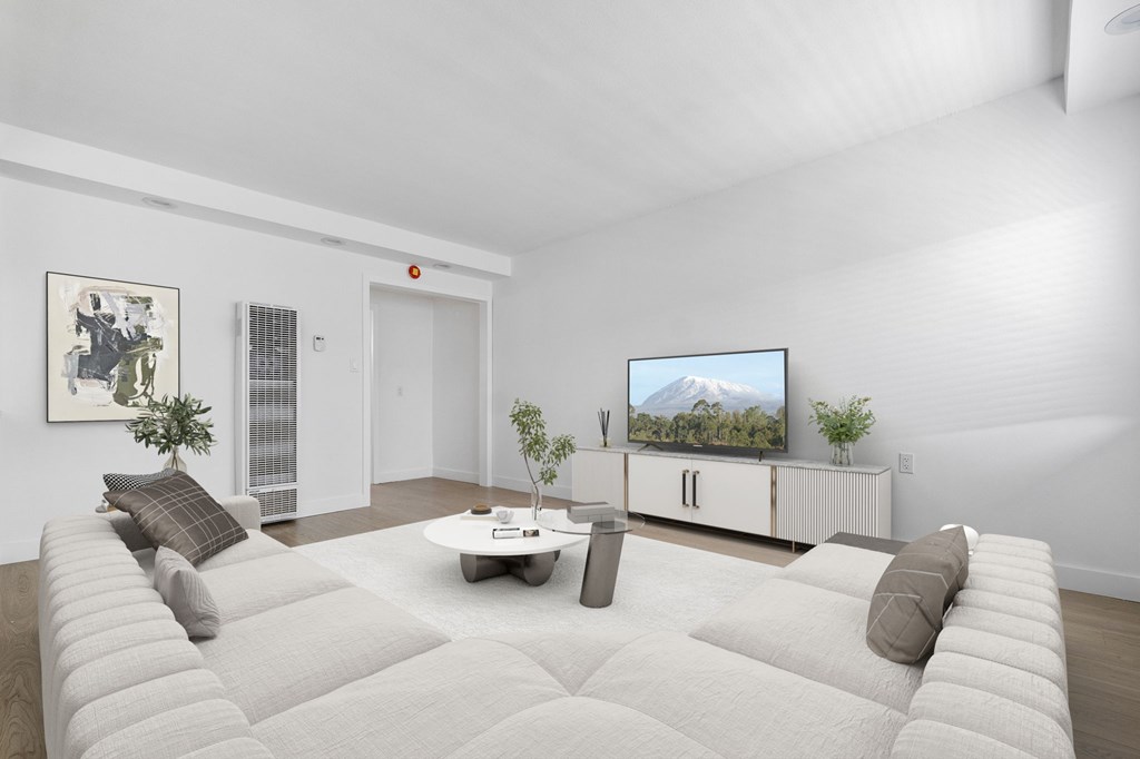 A living room with a white couch and a television on a cabinet.