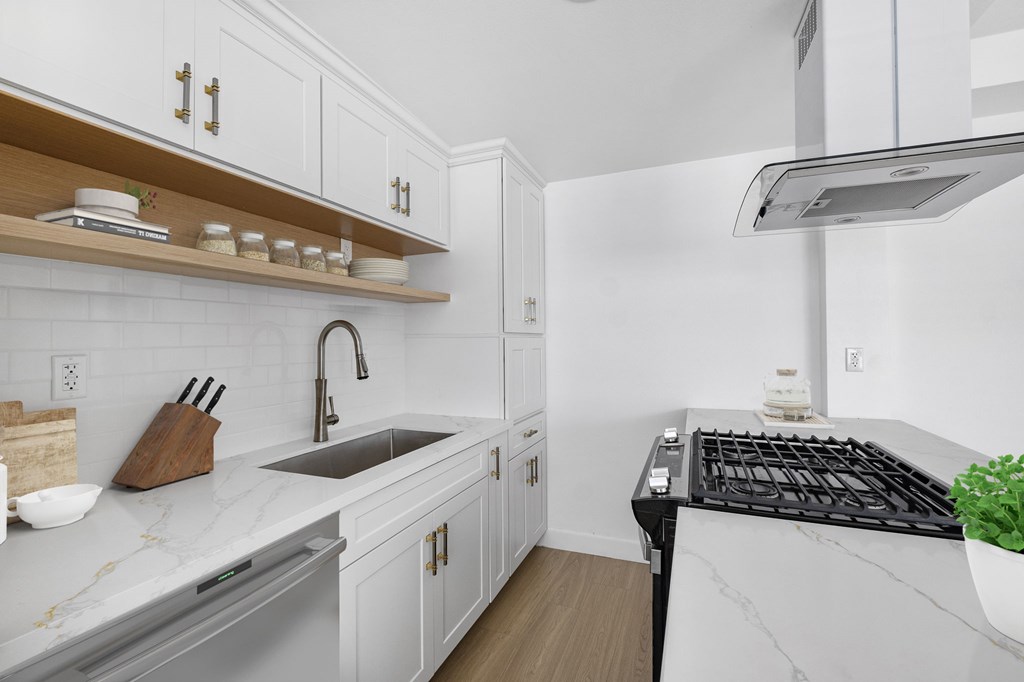 A modern kitchen with white cabinets and a black stove top.