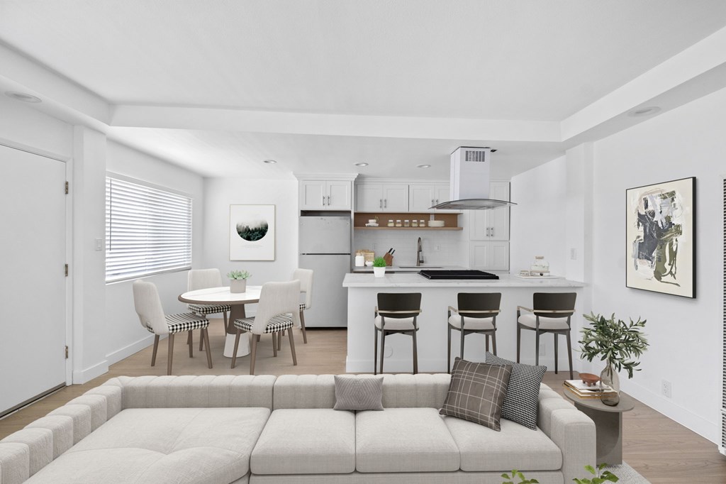A modern living room with a grey sofa and a dining table with chairs.