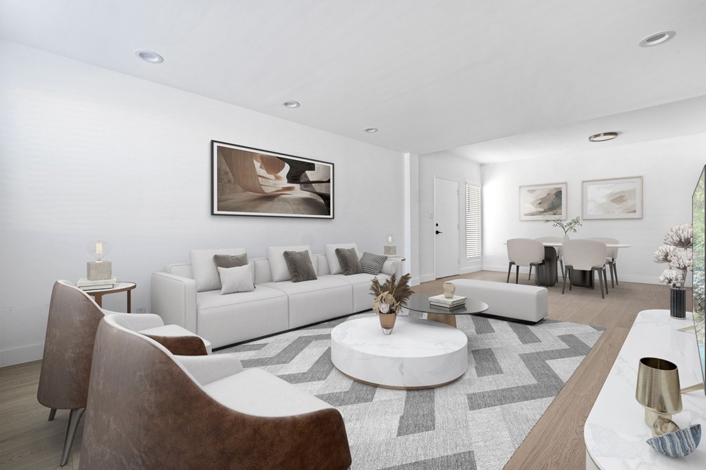 A modern living room with a large white sofa, a coffee table, and a painting on the wall.