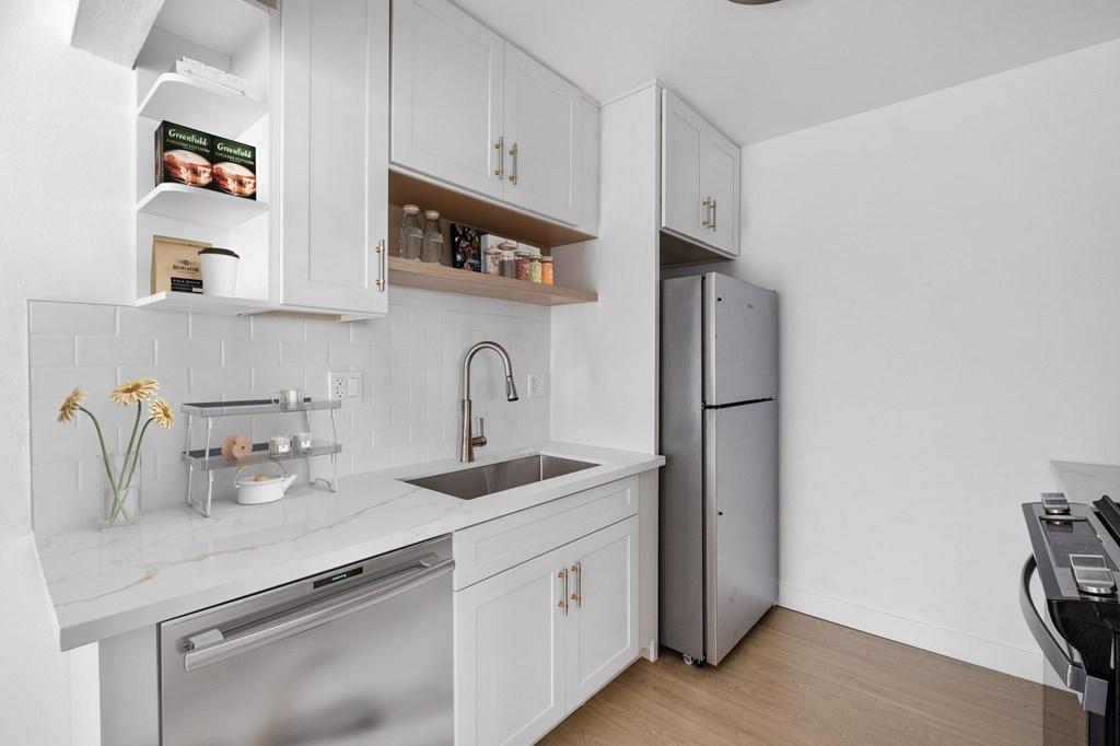 A modern kitchen with white cabinets and stainless steel appliances.