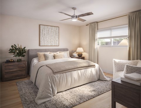 A bedroom with a large bed, a ceiling fan, and a nightstand with a plant on it.