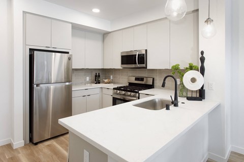 A modern kitchen with a stainless steel refrigerator and a white countertop.