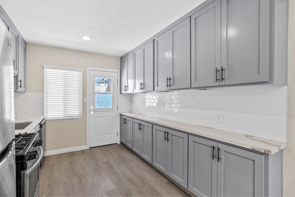 a kitchen with gray cabinets and a stove and a door