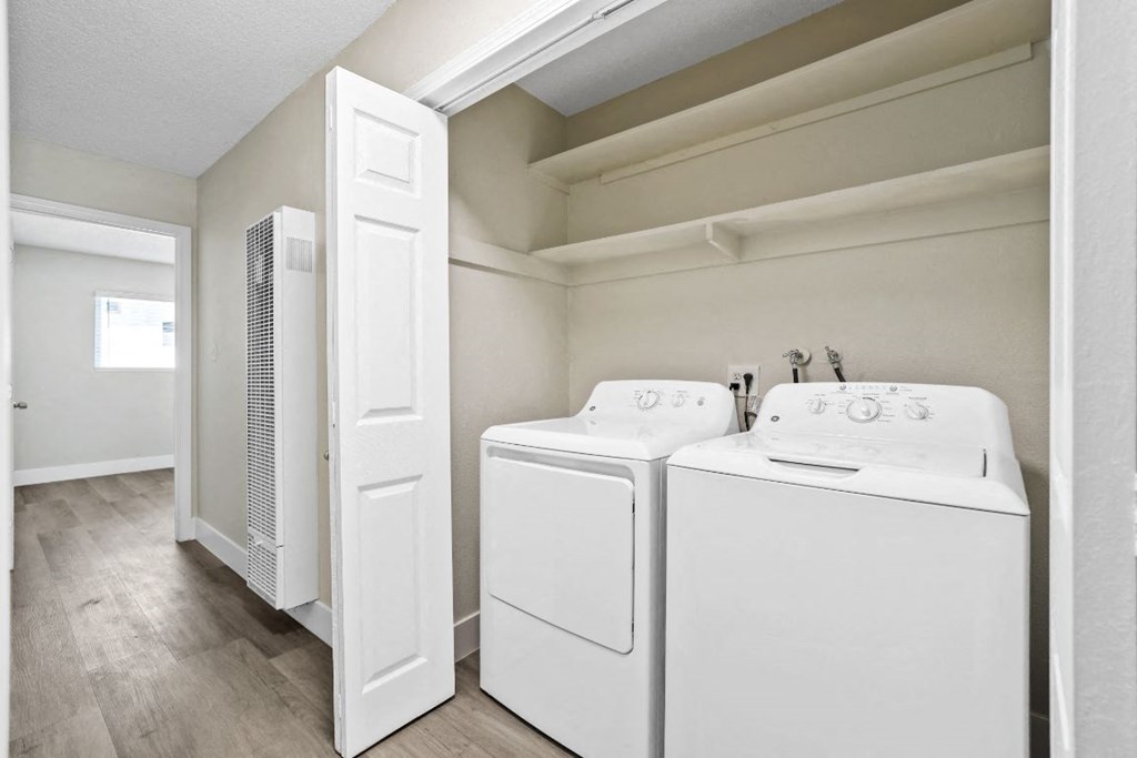 a white laundry room with two washes and a dryer