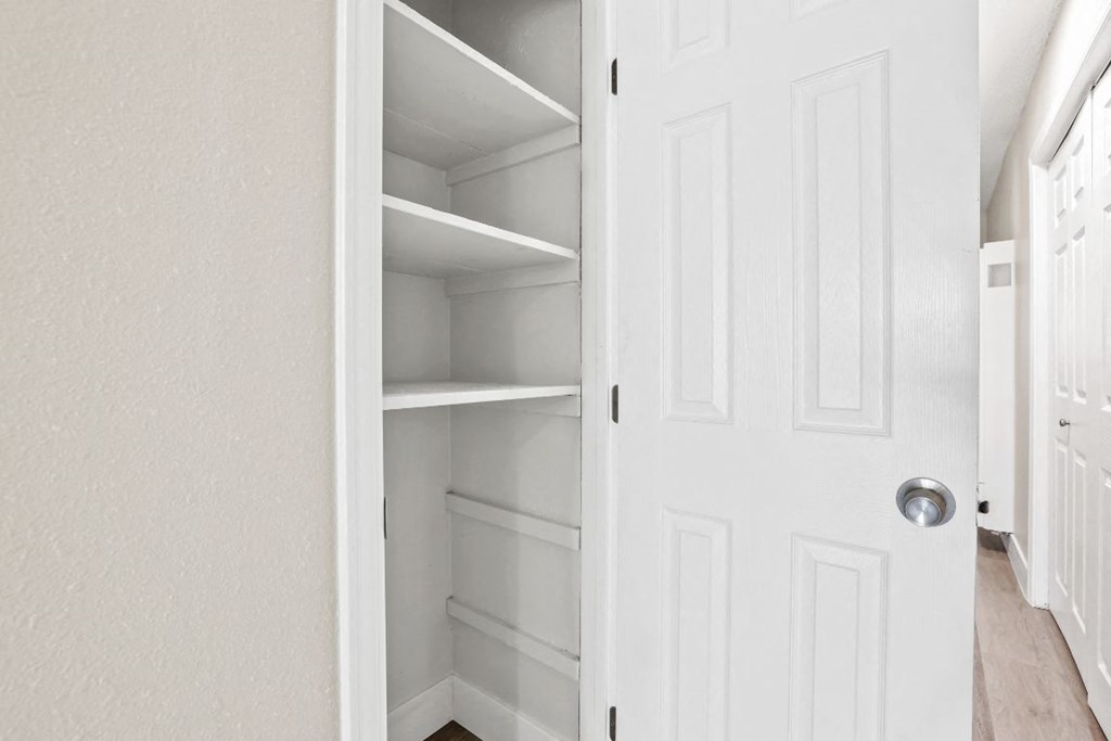 a closet with white shelves and a white door