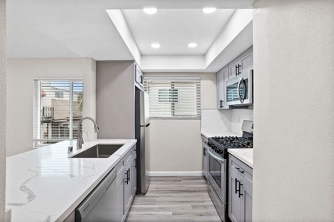a white kitchen with stainless steel appliances and a window